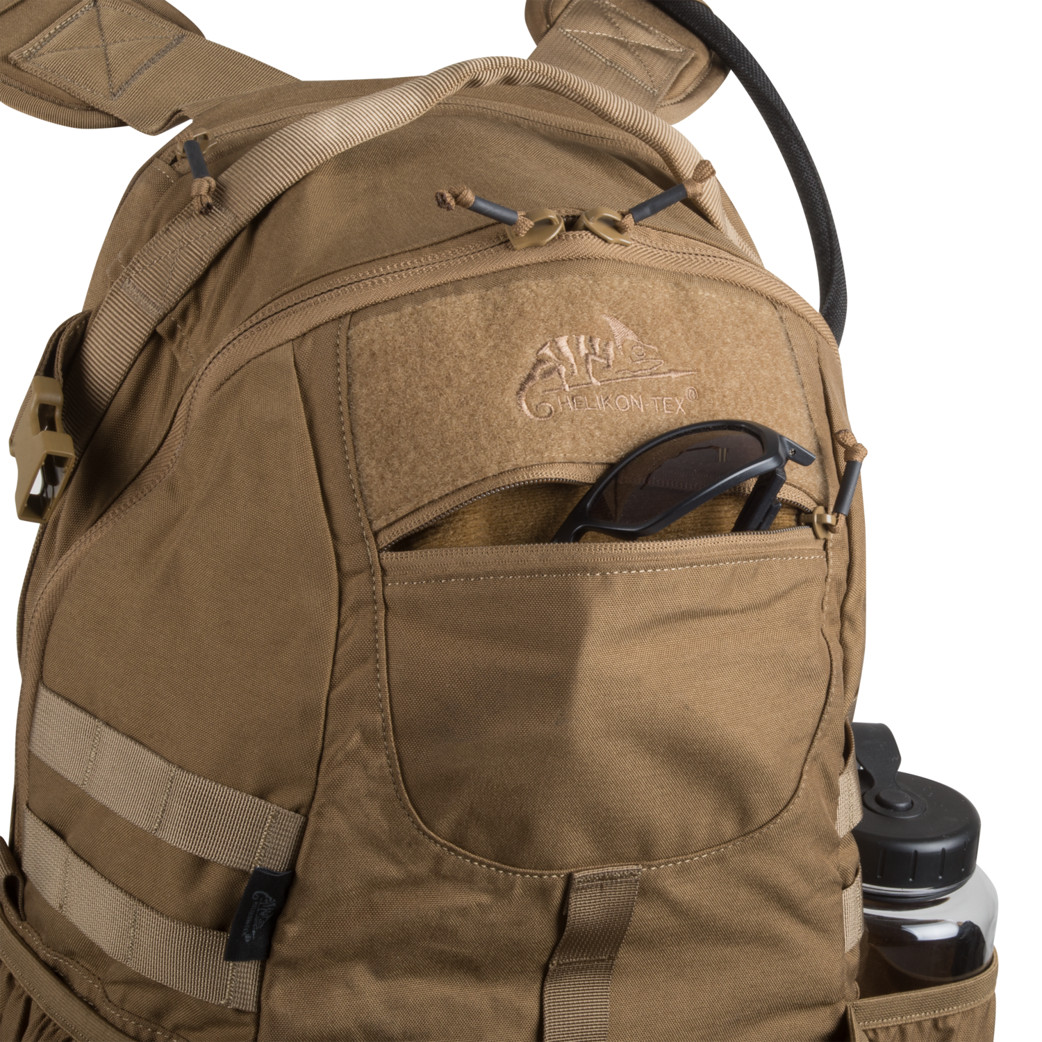 Hellbrauner HELIKON-TEX Raider Backpack® mit einer Vordertasche mit Reißverschluss für eine Sonnenbrille, einer Seitentasche für eine Wasserflasche und einem angebrachten Trinkschlauch; mit dem Versatile Insert System und dem CamoVntex-Logo auf der Vorderseite.