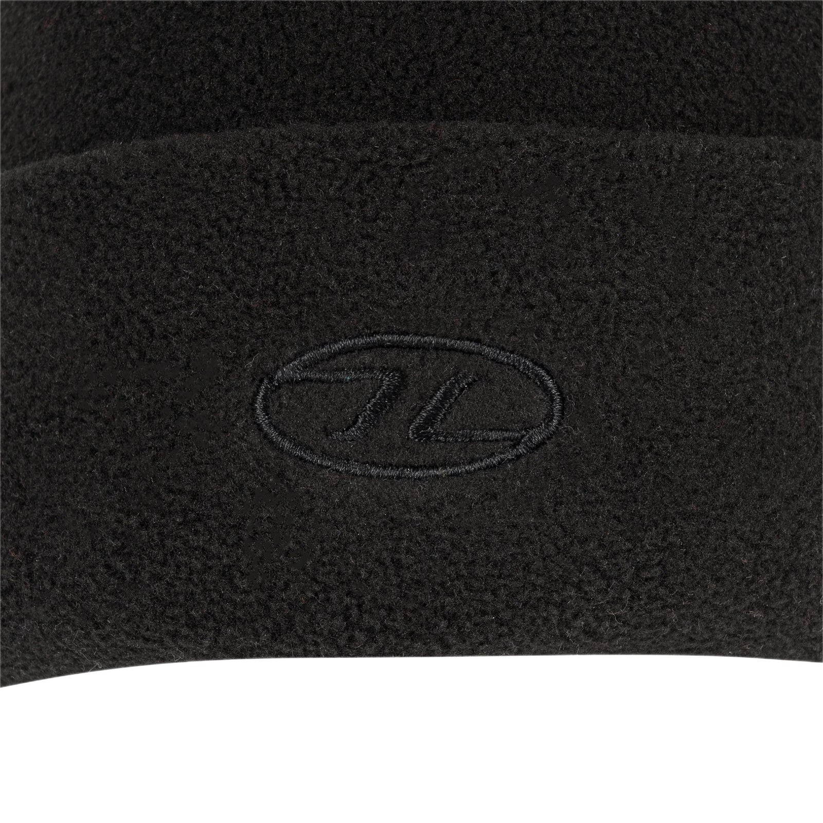 Nahaufnahme der Highlander Fleece Beanie von HIGHLANDER OUTDOOR aus weichem Polyester-Fleece in Schwarz mit einem dezent gestickten ovalen Logo am Bündchen.
