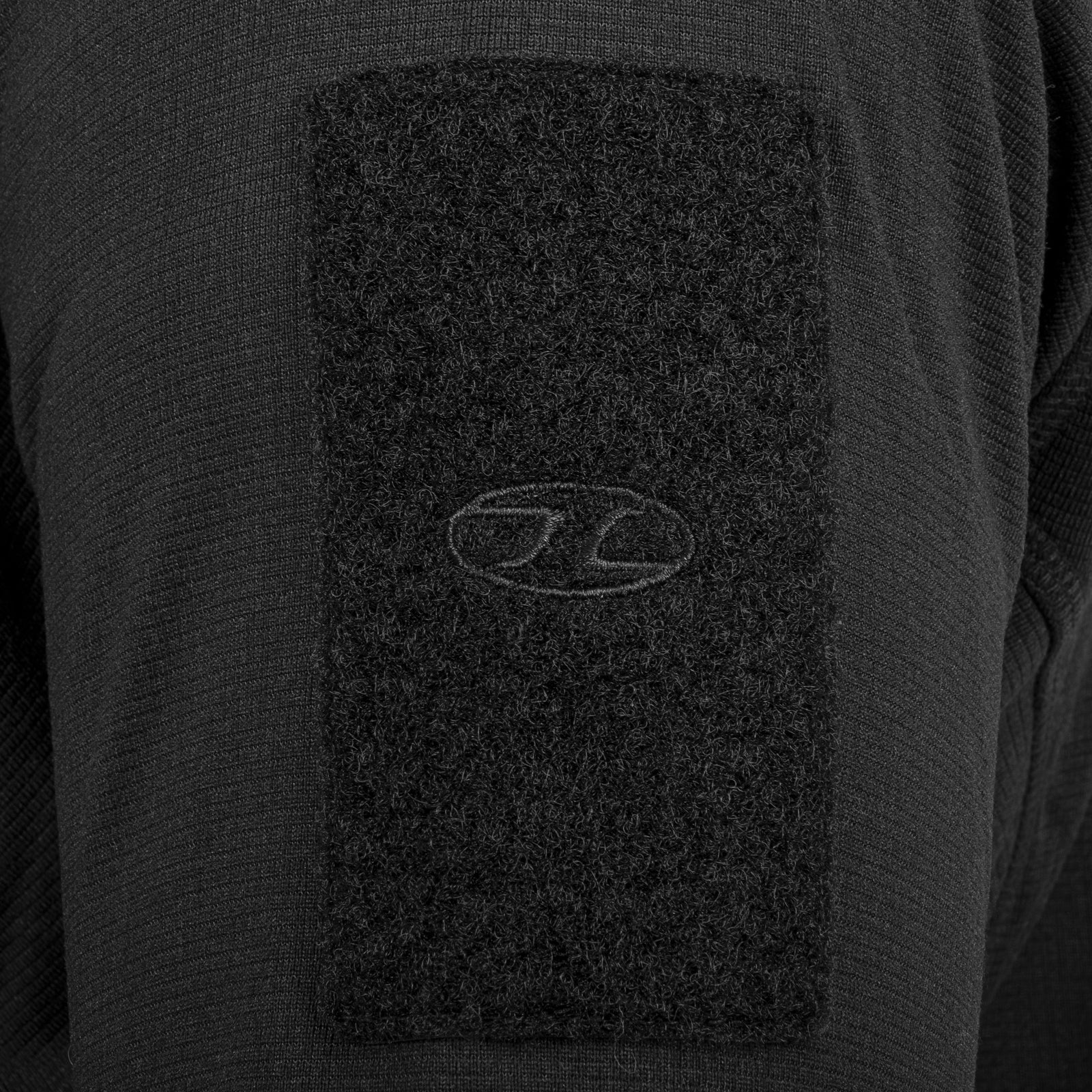 Nahaufnahme eines schwarzen Ärmels des Highlander Forces Tactical Hirta Fleece mit einem rechteckigen Klettaufnäher mit gesticktem HIGHLANDER FORCES-Logo in der Mitte.