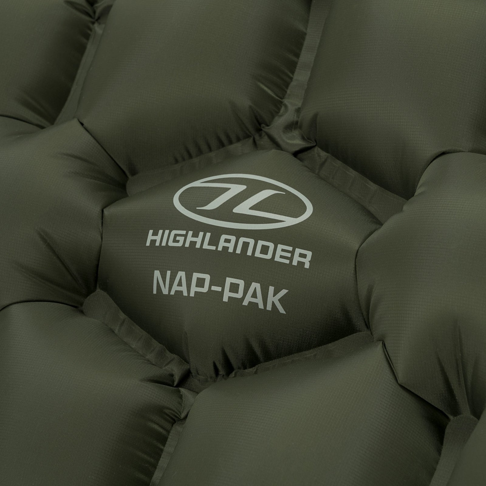 Nahaufnahme der aufblasbaren Highlander NAP-PAK-Schlafmatte von HIGHLANDER FORCES. Sie besteht aus robustem, grünem Ripstop-Nylon und ist mit dem Markenlogo und "HIGHLANDER NAP-PAK" in Weiß bedruckt.