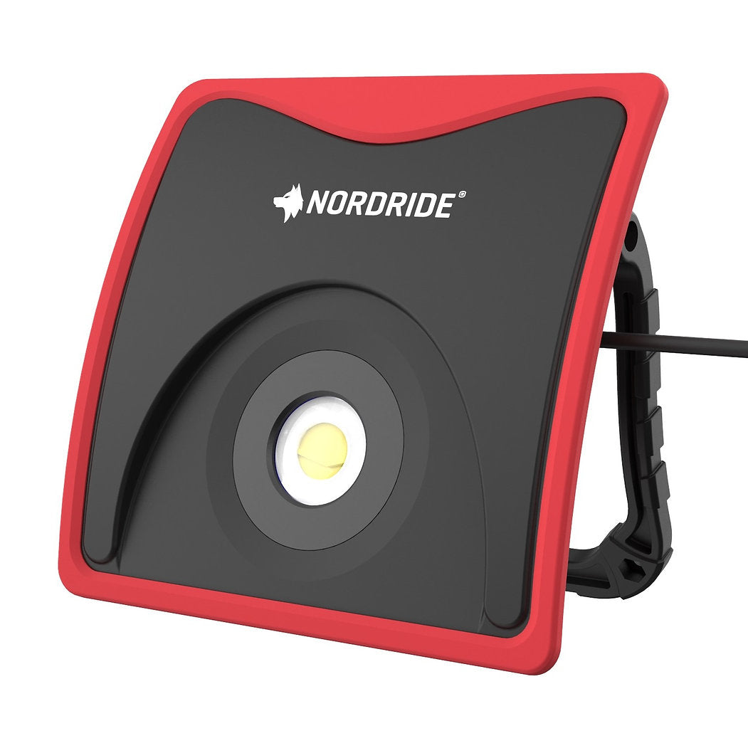 Der NORDRIDE Power Light 60W Arbeitsstrahler ist eine tragbare LED-Arbeitsleuchte mit schwarzem und rotem Gehäuse, NORDRIDE-Logo auf der Vorderseite, einem Griff oder Ständer an der Seite und liefert eine helle 5000 Lumen Leistung für jeden Arbeitsbereich.