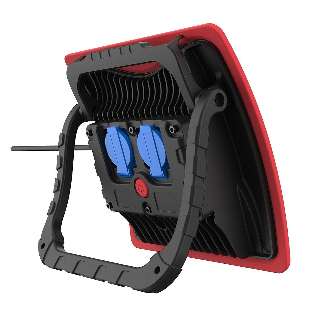 Der NORDRIDE Nordride Arbeitsstrahler Power Light 60W ist ein tragbarer LED-Arbeitsscheinwerfer mit schwarzem Griff, rotem Rahmen und zwei blau abgedeckten Steckdosen auf der Rückseite. Er liefert bis zu 5000 Lumen für eine zuverlässige Beleuchtung der Baustelle.
