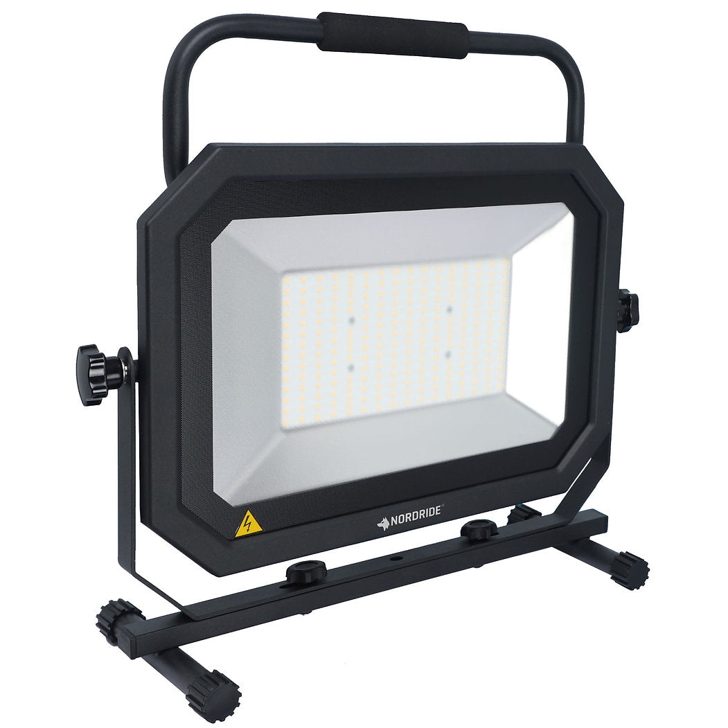 Der NORDRIDE Nordride Baustrahler Sector 150W IP65 ist eine tragbare LED-Arbeitsleuchte mit schwarzem, rechteckigem Rahmen, seitlichen Einstellknöpfen, oberem Griff, stabilem Sockel und dem NORDRIDE-Logo auf der Vorderseite.