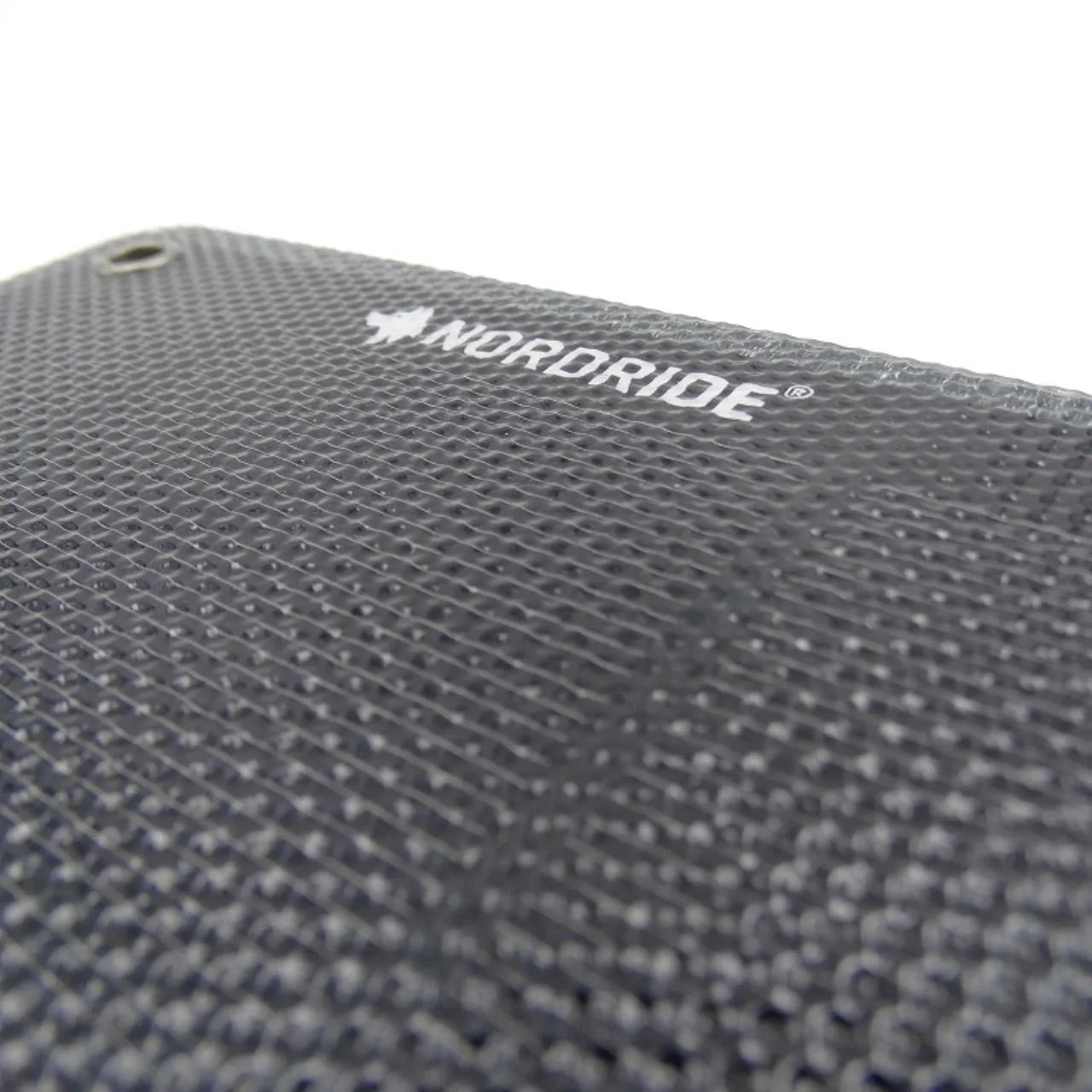 Nahaufnahme der strukturierten schwarzen Nordride SOLAR PULSE 7W-Oberfläche mit dem NORDRIDE-Logo und einem kleinen Loch in der oberen linken Ecke, perfekt für die Verwendung als tragbares Solarpanel. Das Bild hebt das Logo vor einem weißen Hintergrund hervor.