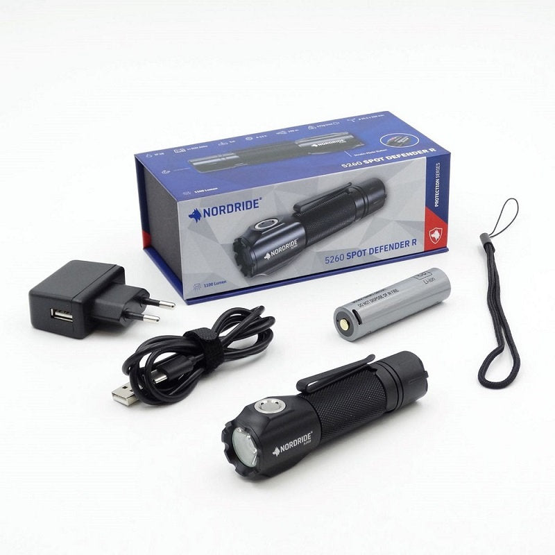 Eine schwarze NORDRIDE Nordride Taschenlampe Spot Defender R wird mit ihrer Verpackung, dem Akku, dem USB-Kabel, dem Netzteil und der Handschlaufe auf einer weißen Fläche präsentiert.