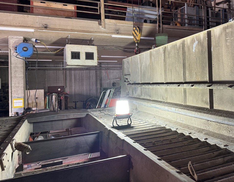 Die NORDRIDE VISION Cover 360° zu LUMOS taucht einen industriellen Arbeitsbereich in ein volles Licht und beleuchtet Metallroste, Geräte, Regale und Maschinen, um eine helle Werkstattatmosphäre zu schaffen.