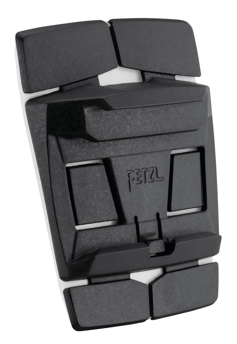 Nahaufnahme eines PETZL-Zubehörteils aus schwarzem Kunststoff und Gummi mit eingeprägtem "Petzl" in der Mitte, das für die Verwendung mit Stirnlampenhelmen entwickelt wurde - speziell für das Petzl Helmet Adapt selbstklebendes Befestigungssystem für Outdoor-Ausrüstung.