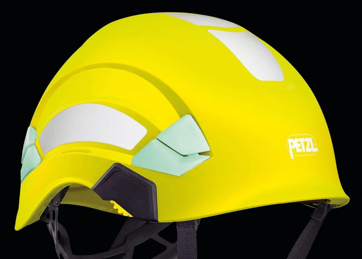 Ein Satz PETZL reflektierende Aufkleber von PETZL, abgebildet auf einem leuchtend gelben Helm mit weißen reflektierenden Aufnähern und einem schwarzen verstellbaren Riemen, dargestellt vor einem schwarzen Hintergrund.