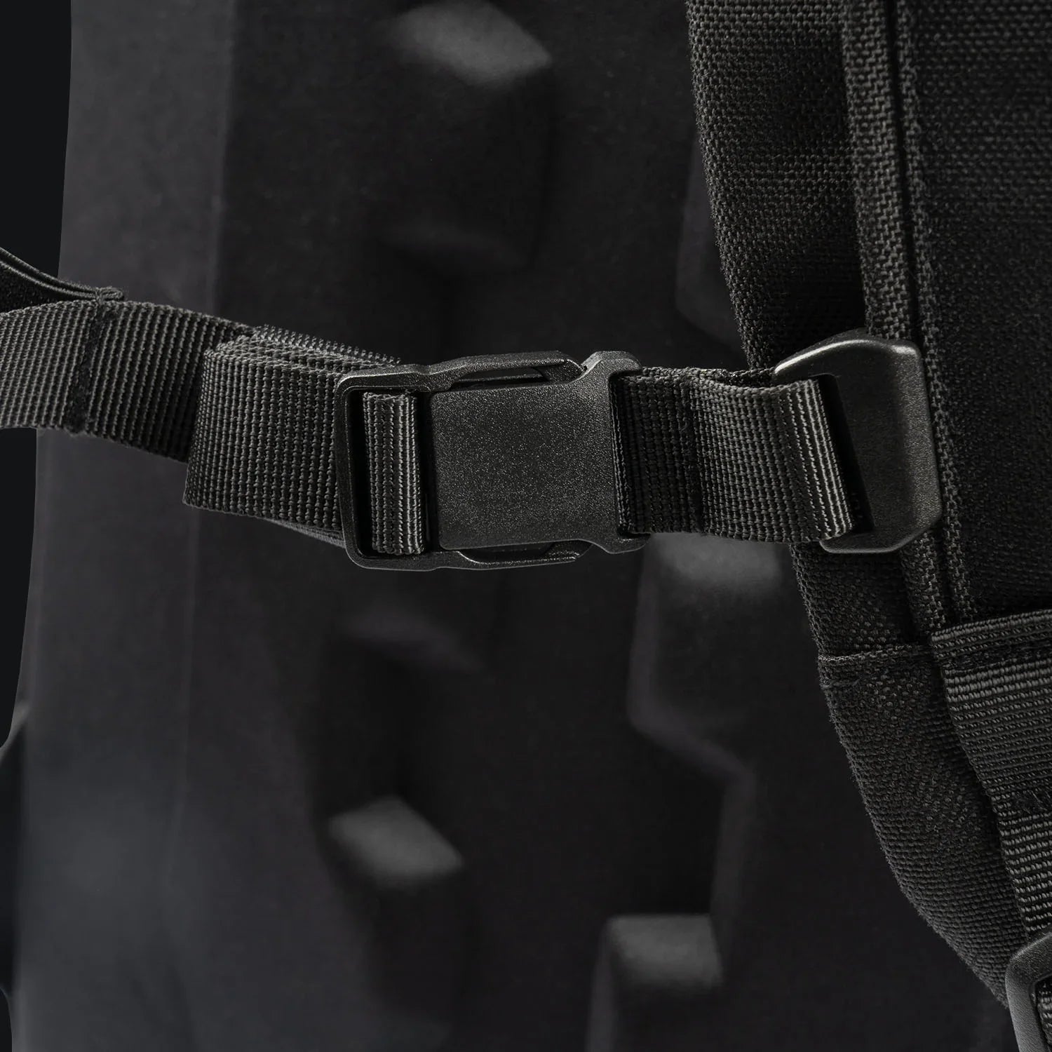 Nahaufnahme eines schwarzen Kunststoffverschlusses am Gurt des STOIRM 25L Tactical Pack GEN2 mit gepolsterten, strukturierten Details - perfekt für Ihre Outdoor-Ausrüstung.