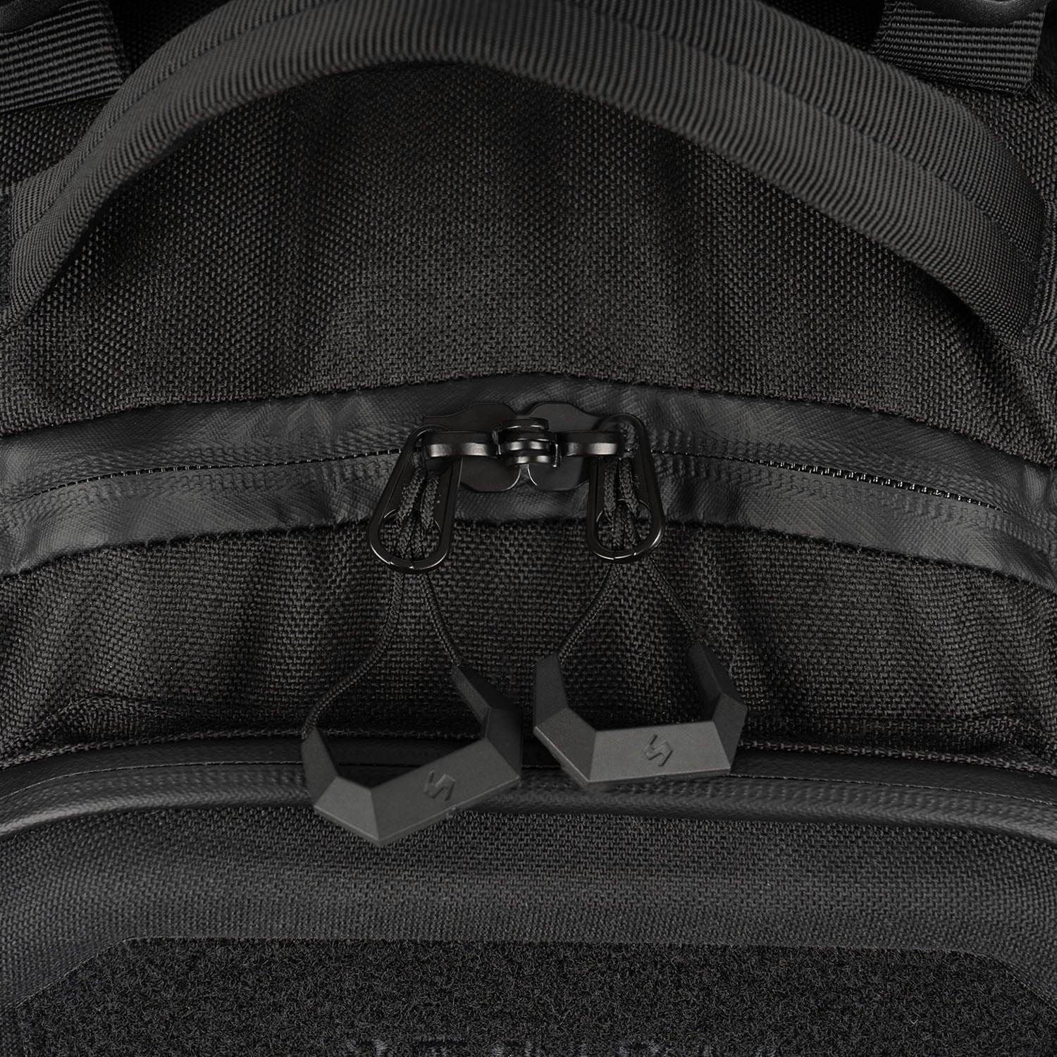 Nahaufnahme des STOIRM 25L Tactical Pack GEN2 von STOIRM, mit zwei sechseckigen Reißverschlüssen, einem robusten Stoffgriff oben und detaillierten Nähten - ideal für Ihre Outdoor-Ausrüstung.