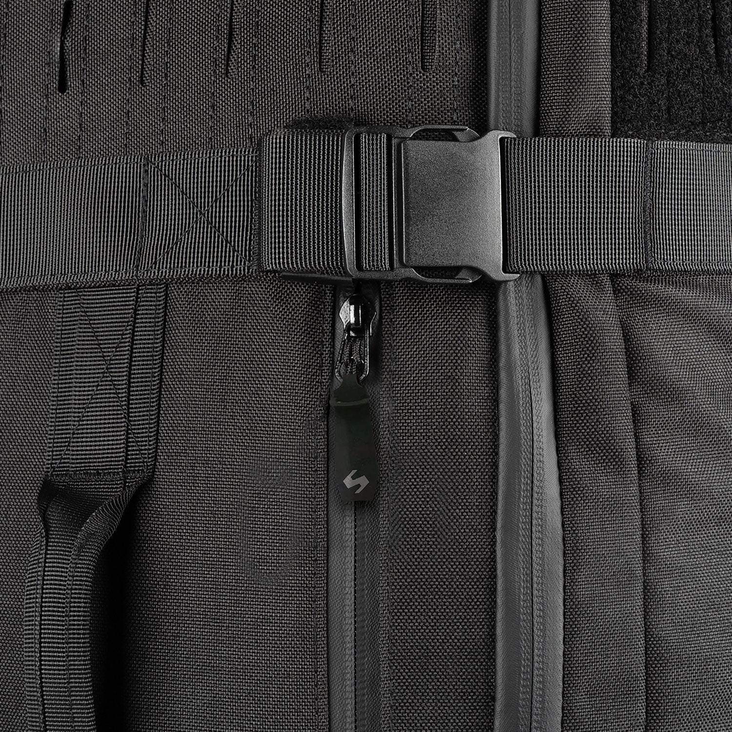 Nahaufnahme eines schwarzen Rucksacks mit Kunststoffschnalle, Reißverschluss und Gurtbändern auf strukturiertem Stoff - perfekt als wasserfeste Alltagstasche oder zusätzliches Fach für Ihren STOIRM 50L Duffel Bag von STOIRM.