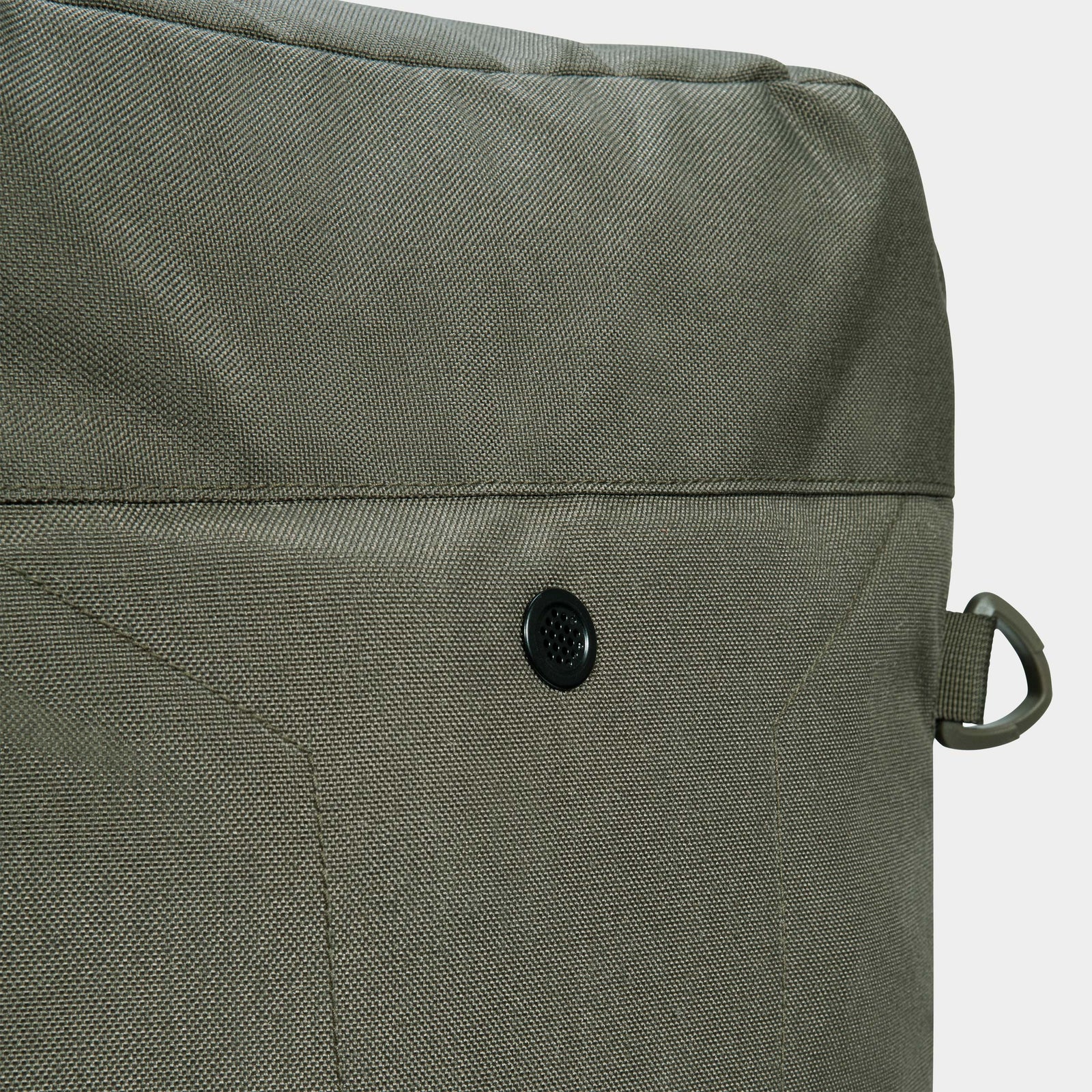 Nahaufnahme einer strukturierten olivgrünen STOIRM 50L Duffel Bag von STOIRM, die eine kleine schwarze Öse und eine graue Kunststoffschlaufe an der Seite aufweist. Das robuste, wasserabweisende Material hebt sich von einem schlichten, hellen Hintergrund ab.
