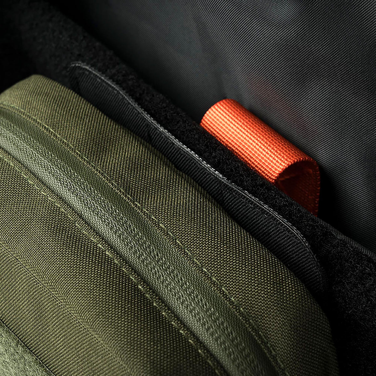 Nahaufnahme des Innenraums der STOIRM Large Molle Panel mit grünen und schwarzen Stofffächern und einer orangefarbenen Stoffschlaufe - Teil des vielseitigen STOIRM Eco-Systems.