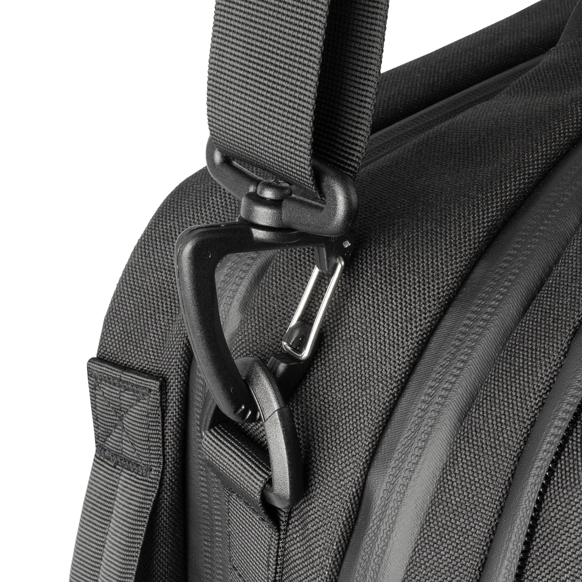 Nahaufnahme des Schultergurts der STOIRM Messenger Bag mit einem stabilen Kunststoff-Drehhaken an einer Stoffschlaufe mit sichtbaren Strukturnähten und Reißverschlüssen. Perfekt für alle, die ein 17-Zoll-Laptopfach benötigen. Marke: STOIRM.