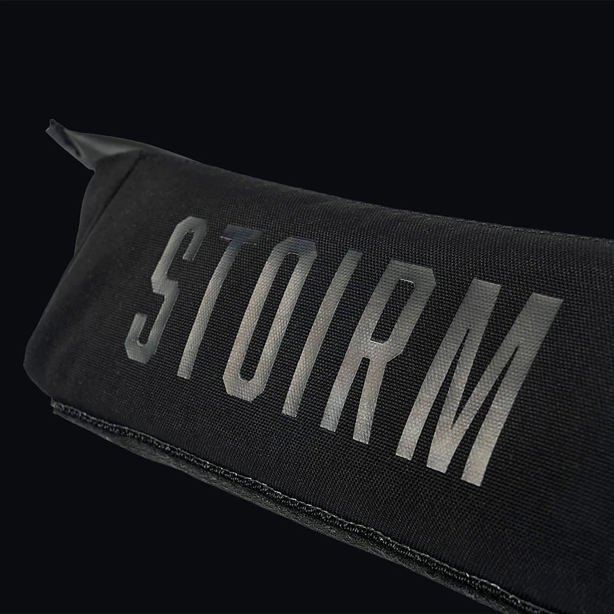 Eine Nahaufnahme der STOIRM Utility Pouch von STOIRM, die aus strapazierfähigem 500D Nylon in Schwarz gefertigt ist und auf der Vorderseite einen auffälligen grauen "STOIRM"-Schriftzug auf schwarzem Hintergrund aufweist.