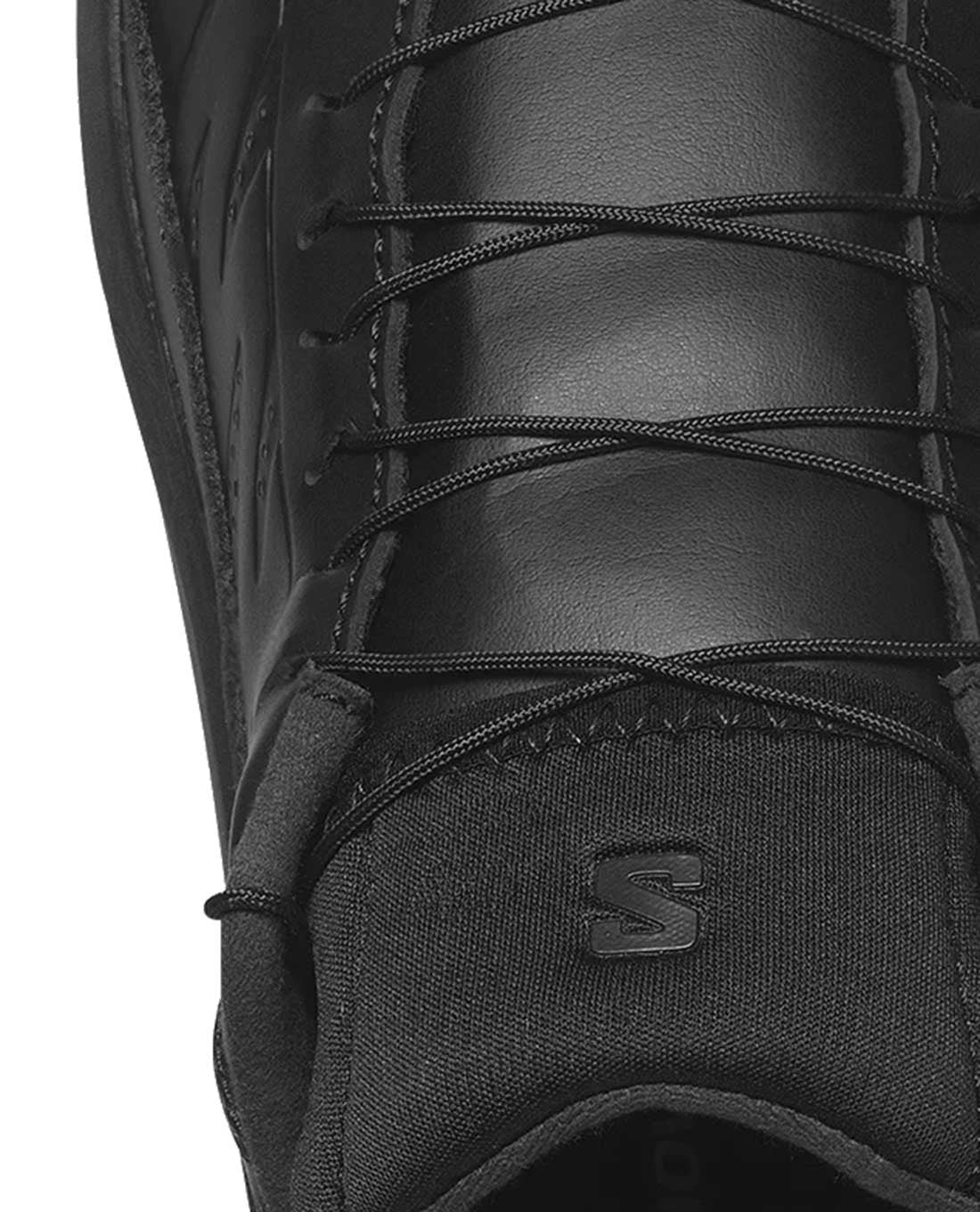 Nahaufnahme des Oberteils des schwarzen Salomon SENSE RIDE 5 SR LEATHER Trail-Schuhs von SALOMON FORCES, mit eng geschnürten schwarzen Schnürsenkeln und einem S-Logo auf der Zunge - ideal für Ihr nächstes Outdoor-Abenteuer.
