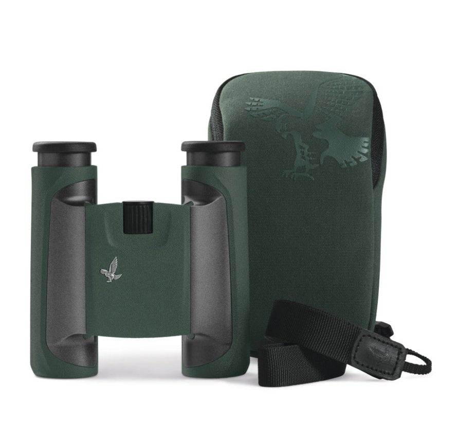 Das SWAROVSKI OPTIK Fernglas CL Pocket 10x25 in Dunkelgrün mit schwarzen Akzenten steht aufrecht neben einem passenden grünen Tragekoffer im Adler-Design, dessen schwarzer Trageriemen im Vordergrund steht.