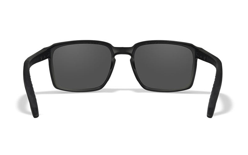 Die WILEY X Sonnenbrille ALFA zeichnet sich durch einen schlanken, rechteckigen schwarzen Rahmen mit grauen Gläsern aus, die nach vorne gerichtet vor einem weißen Hintergrund stehen.