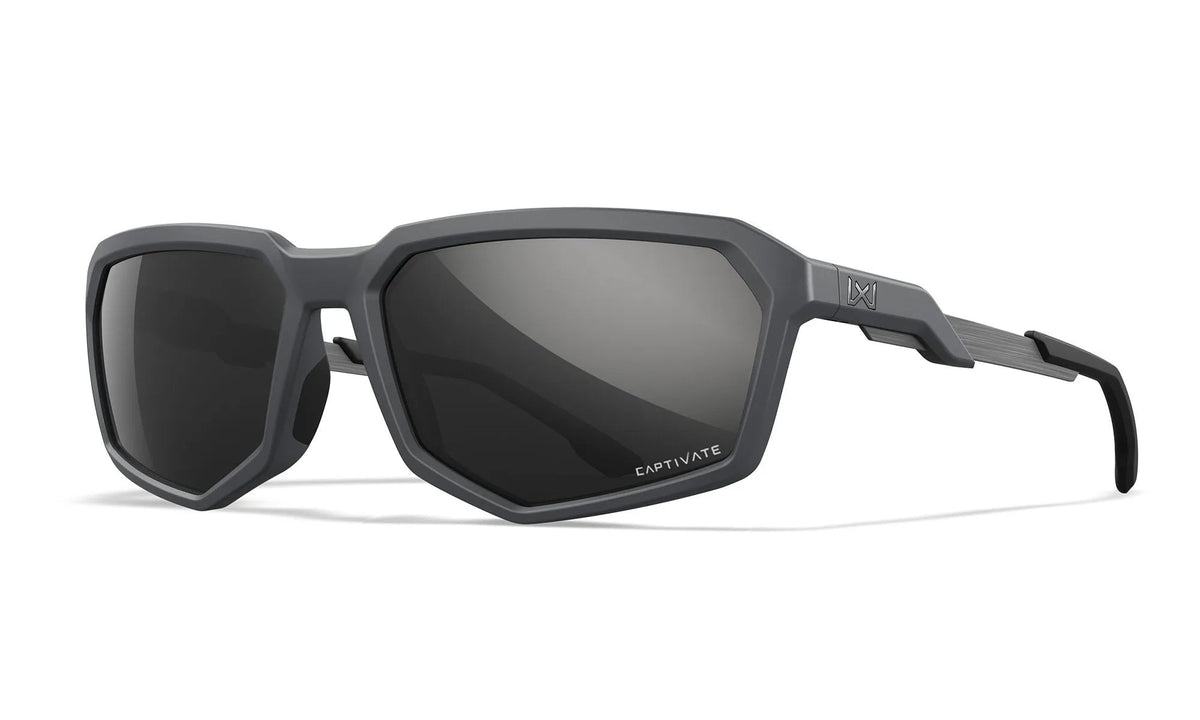 WILEY X Sonnenbrille RECON mit mattem grauen Rahmen und dunklen, polarisierten Gläsern - moderne Outdoor-Brille der Marke WILEY X, diagonal auf weißem Hintergrund präsentiert.