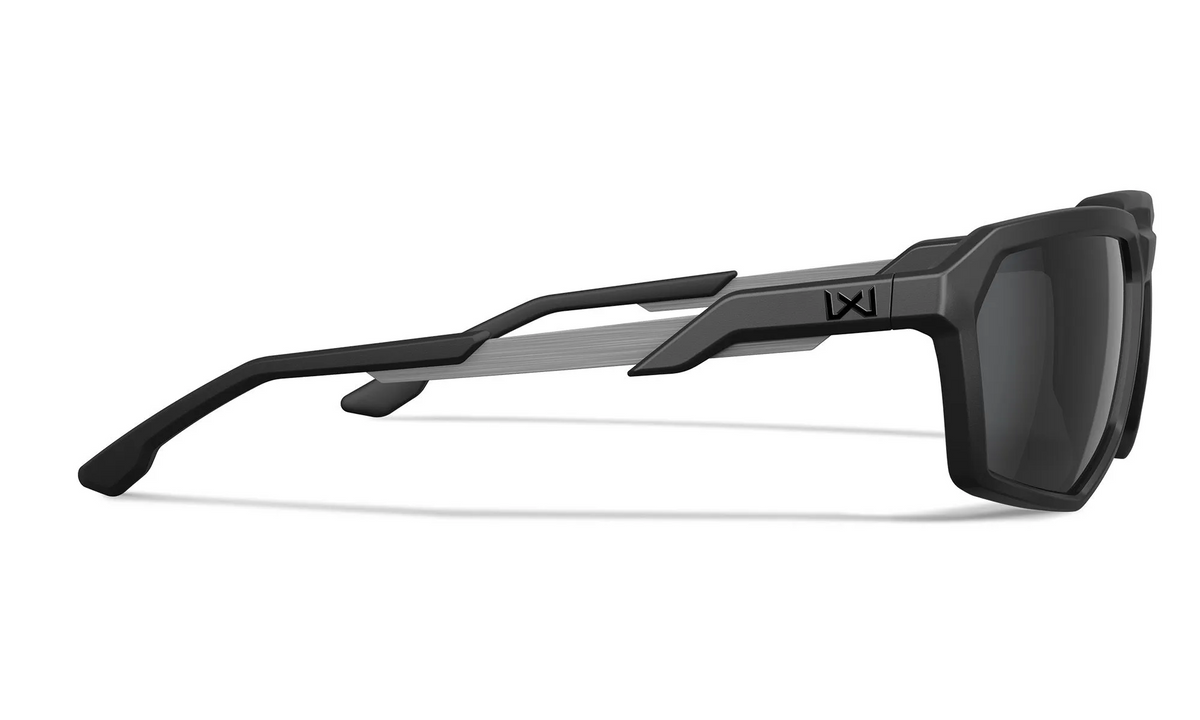 Seitenansicht der WILEY X Sonnenbrille RECON mit einem mattschwarzen und grauen eckigen Rahmen, CAPTIVATE-Gläsern, dunkler Tönung, geometrischem Bügeldesign und dem WX Recon-Logo in der Nähe des Scharniers.