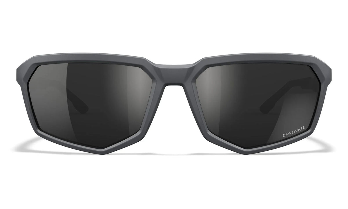 Mattgraue eckige Sonnenbrille mit dunklen Gläsern, von vorne gesehen. Die Wiley X Sonnenbrille RECON von WILEY X hat einen geometrischen Rahmen und CAPTIVATE auf dem unteren rechten Glas - ideal als polarisierte Sonnenbrille für jedes Abenteuer.