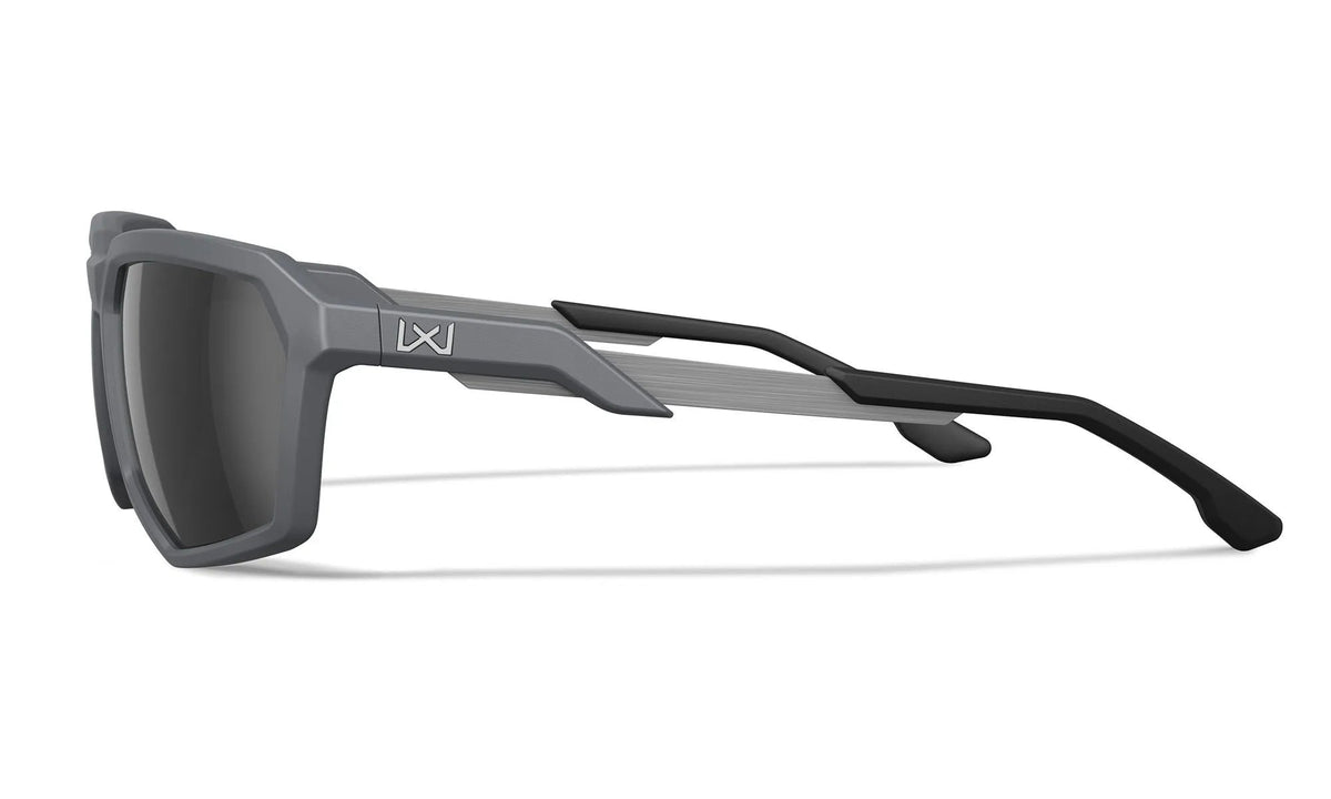Die Wiley X Sonnenbrille RECON von WILEY X zeichnet sich durch graue und schwarze rechteckige polarisierte Gläser, einen dicken geometrischen Rahmen, dunkle Gläser, eckige Bügel und ein kleines Logo in der Nähe des Scharniers aus, wie in der seitlichen Profilansicht zu sehen.