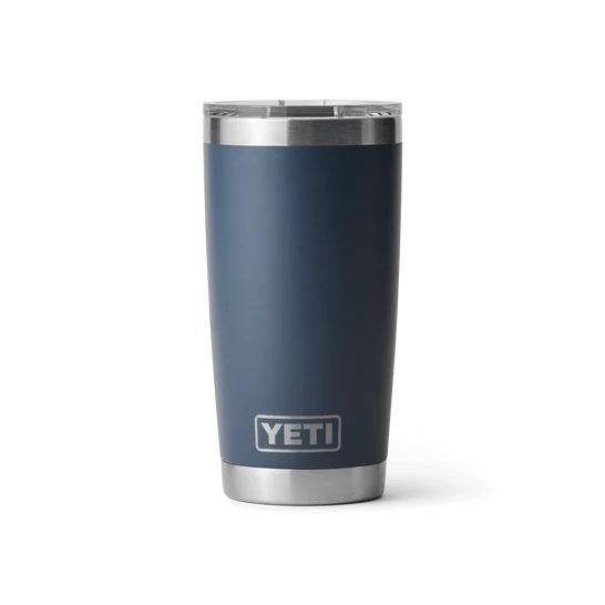 Ein YETI® Becher Rambler 20 Oz - Navy von YETI mit transparentem Deckel und Edelstahl-Boden steht aufrecht vor weißem Hintergrund.