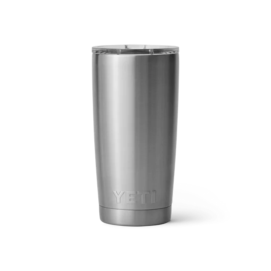 Ein YETI® Becher Rambler 20 Oz aus Edelstahl steht aufrecht auf weißem Hintergrund. Der Becher von YETI hat einen klaren Kunststoffdeckel, und das Markenlogo ist nahe dem Boden geprägt.