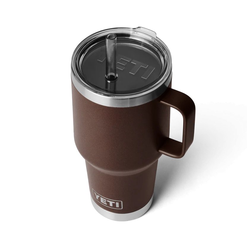 Der YETI® Becher Rambler 35 Oz Straw Mug in Wetlands Brown verfügt über einen Henkel, einen durchsichtigen Strohdeckel mit YETI-Logo und einen Edelstahlboden auf weißem Hintergrund.