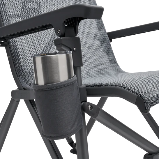 Eine Nahaufnahme des YETI® Campingstuhls Trailhead - Charcoal mit Netzsitz und Rückenlehne, mit integriertem Becherhalter an der Armlehne für einen Edelstahlbecher.