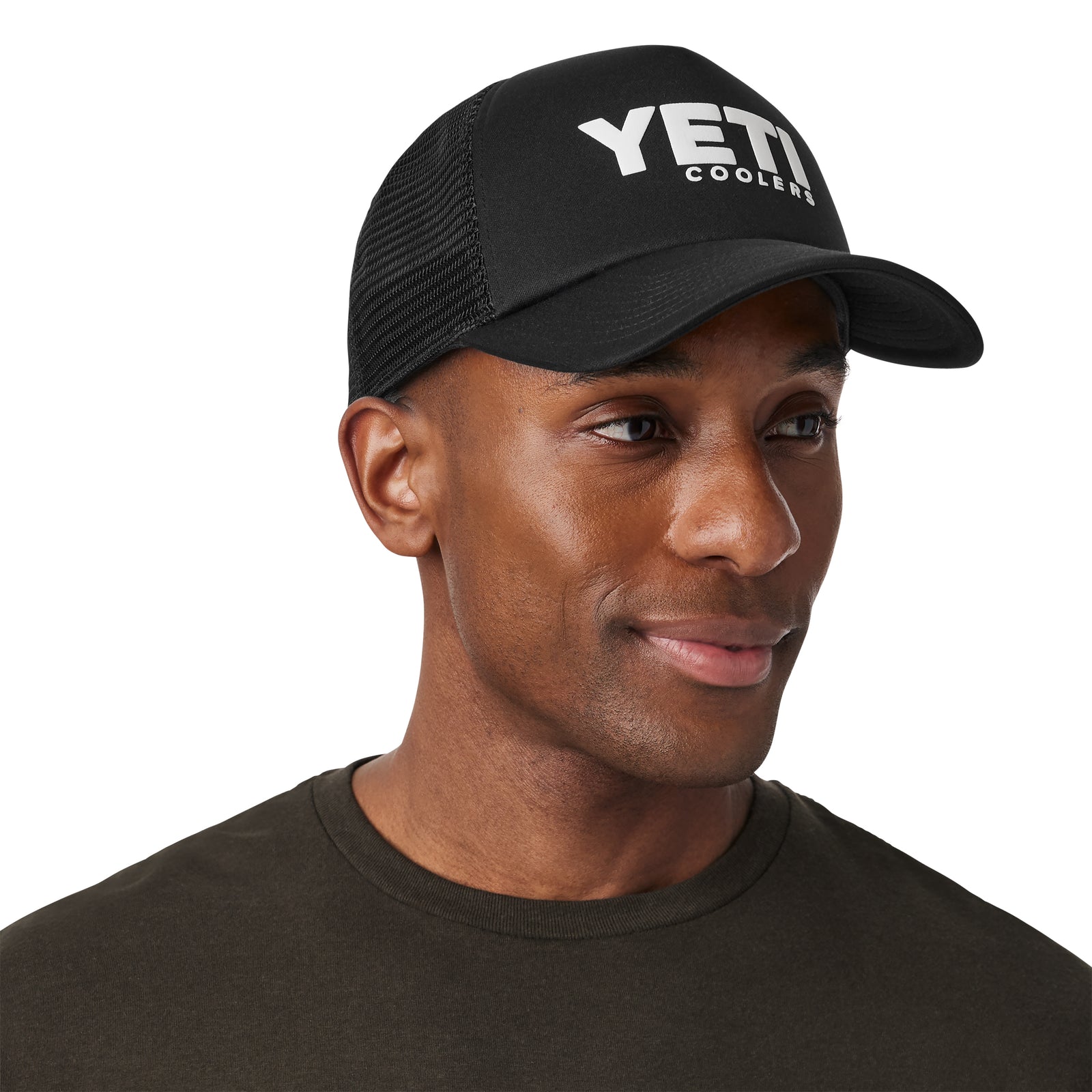 Ein Mann mit einer YETI® Coolers Foam Trucker Cap von YETI und einem dunklen Hemd lächelt und schaut leicht zur Seite vor einem schlichten Hintergrund.
