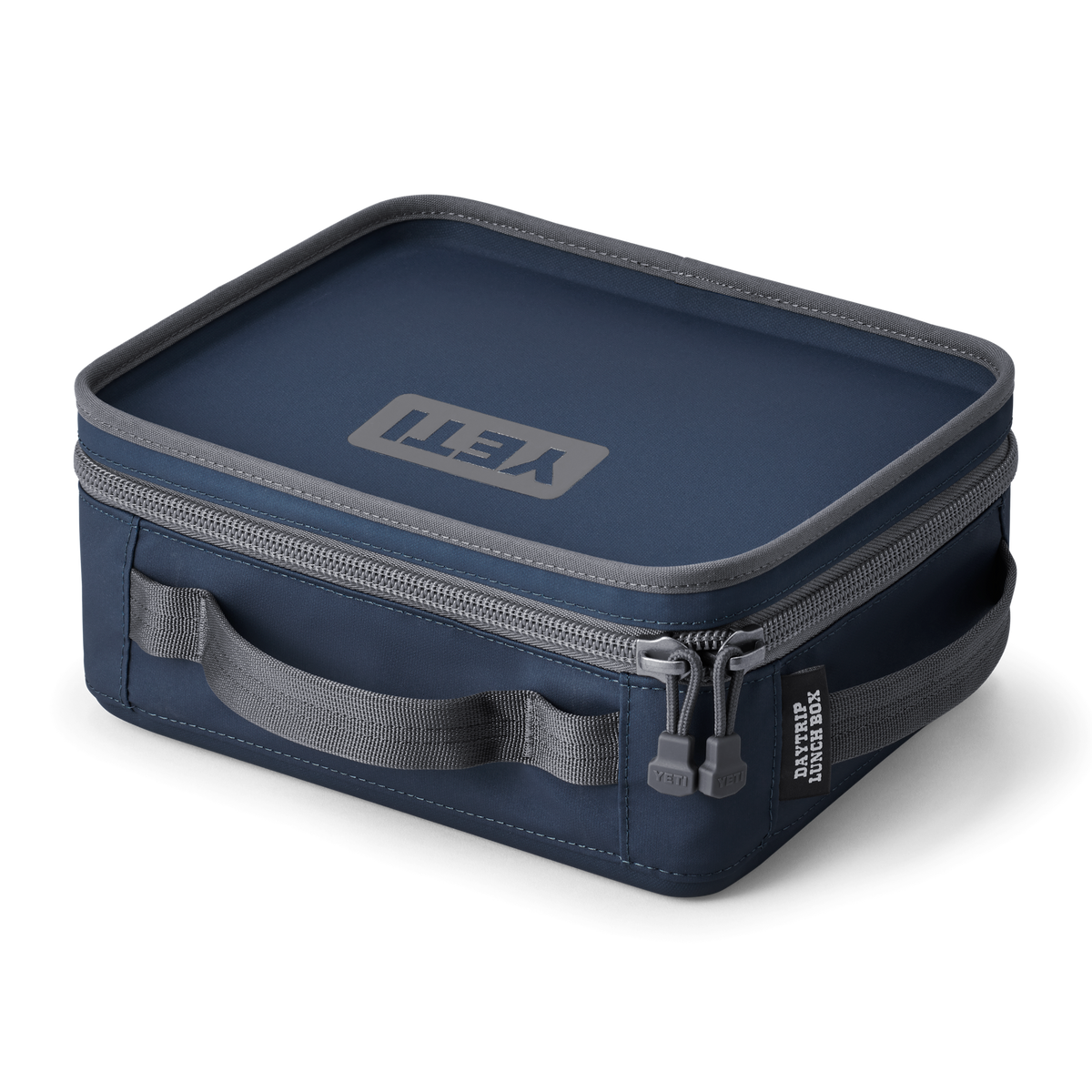 Die YETI® Daytrip Lunch Box - Navy hat eine rechteckige Form, einen grauen Reißverschluss, einen passenden Griff und das YETI-Logo auf dem Deckel. Sie ist ideal, um das Mittagessen frisch zu halten und steht auf einem schlichten weißen Hintergrund.