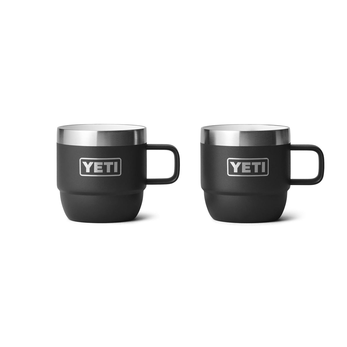 Zwei schwarze YETI® Espresso-Tasse Rambler 6 Oz Becher (2er Pack) von YETI, jeweils mit Henkel und Edelstahlrand, stehen nebeneinander auf weißem Hintergrund und betonen ihre doppelwandige Vakuumisolierung zur Temperaturerhaltung.