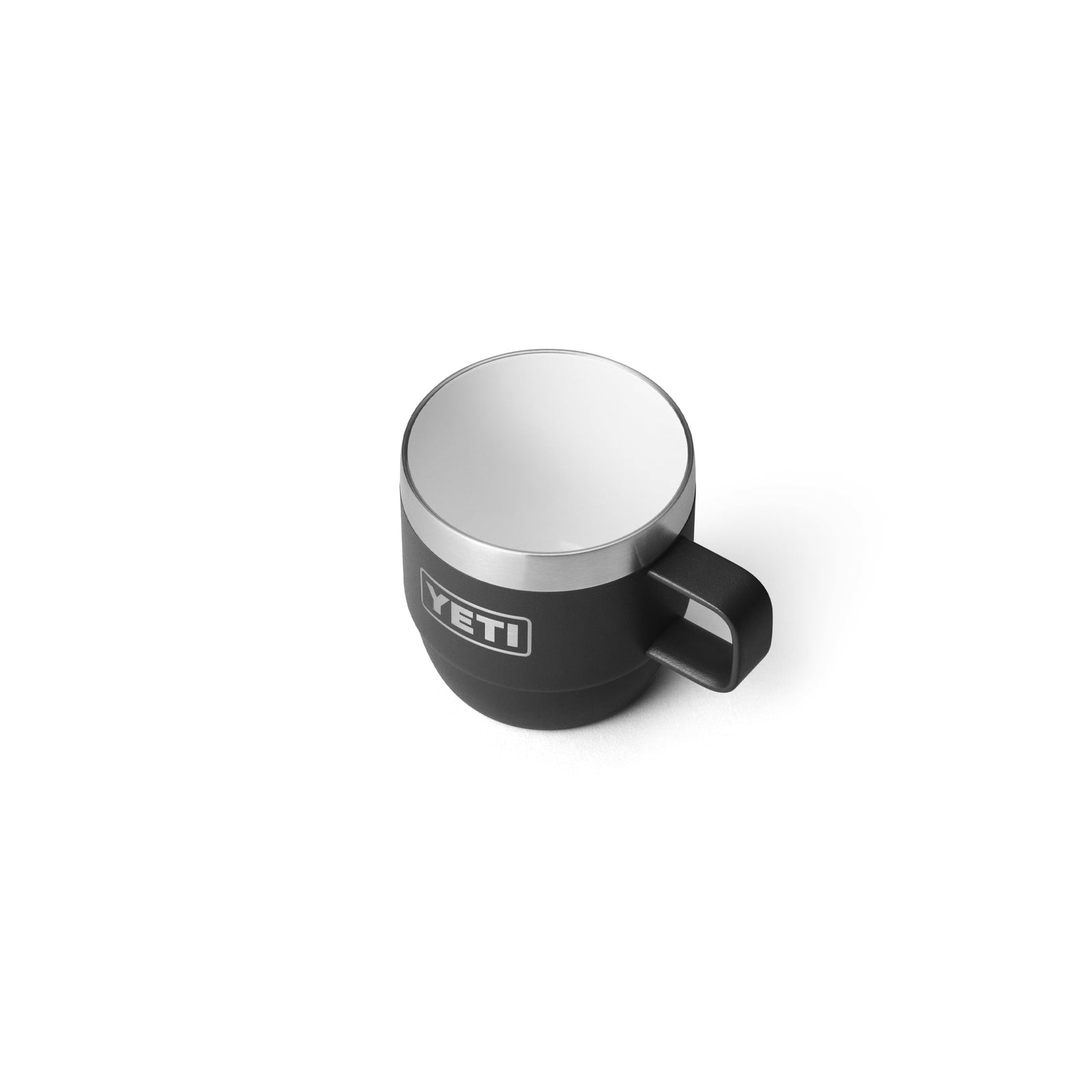 Eine schwarze YETI® Espresso-Tasse Rambler 6 Oz (2er Pack) mit Henkel und silbernem Rand, mit doppelwandiger Vakuumisolierung, wird von oben schräg auf weißem Hintergrund gezeigt.