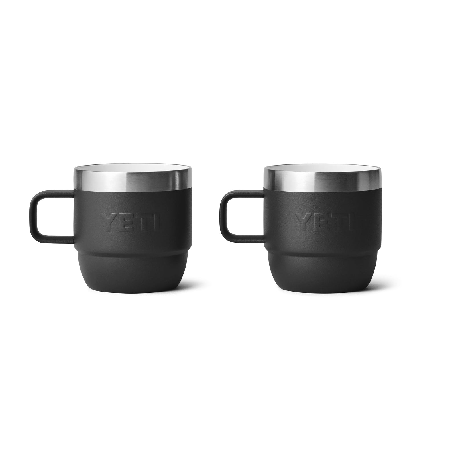 Zwei schwarze YETI® Espresso-Tasse Rambler 6 Oz (2er Pack) Becher mit Henkeln und Edelstahlrand sitzen nebeneinander auf weißem Grund und verfügen über eine doppelwandige Vakuumisolierung, die Getränke länger heiß oder kalt hält.