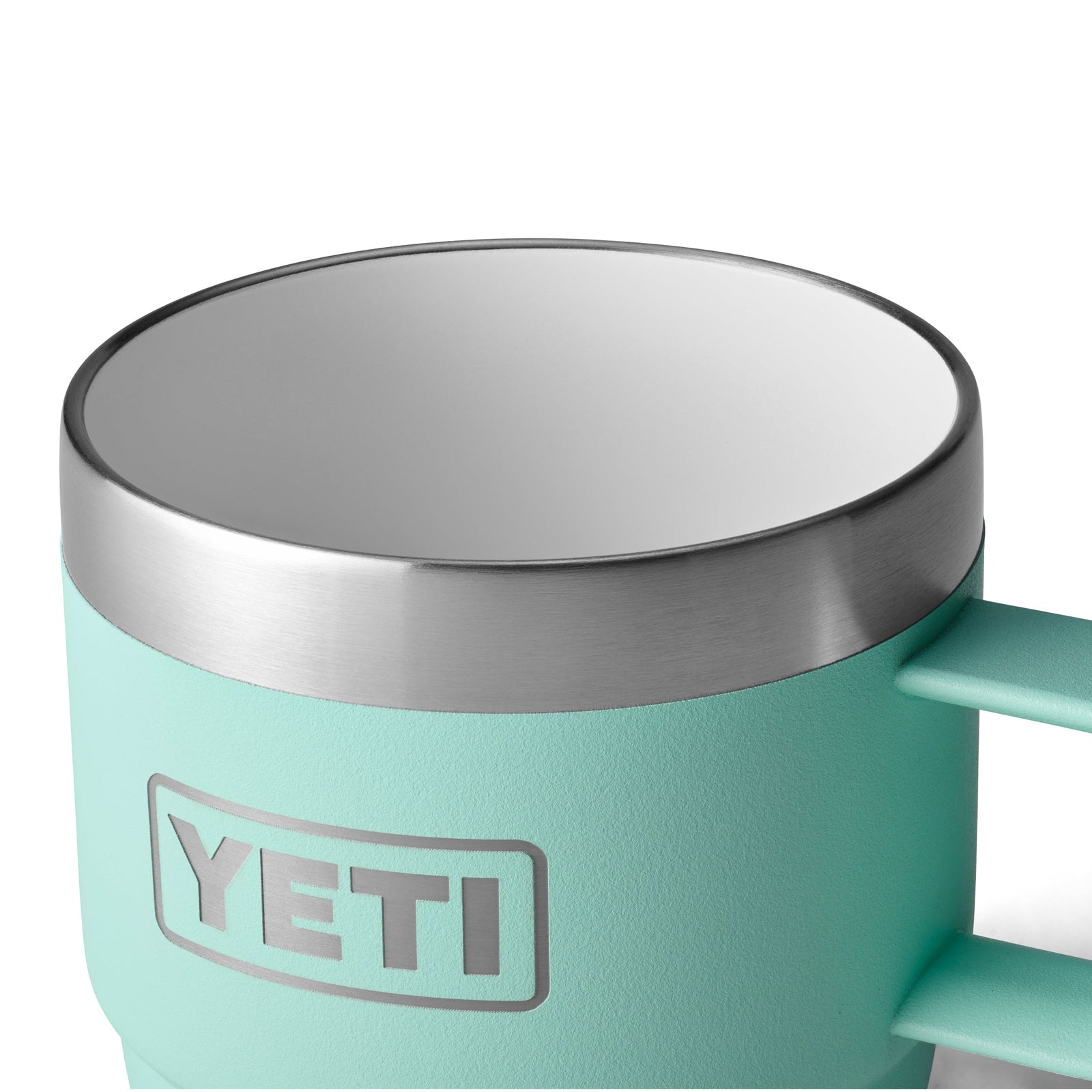 Eine Nahaufnahme einer hellblauen YETI® Espresso-Tasse Rambler 6 Oz (2er Pack) - Seafoam mit doppelwandiger Vakuumisolierung, Edelstahlrand, weißem Innenraum, Griff und YETI-Logo an der Seite.