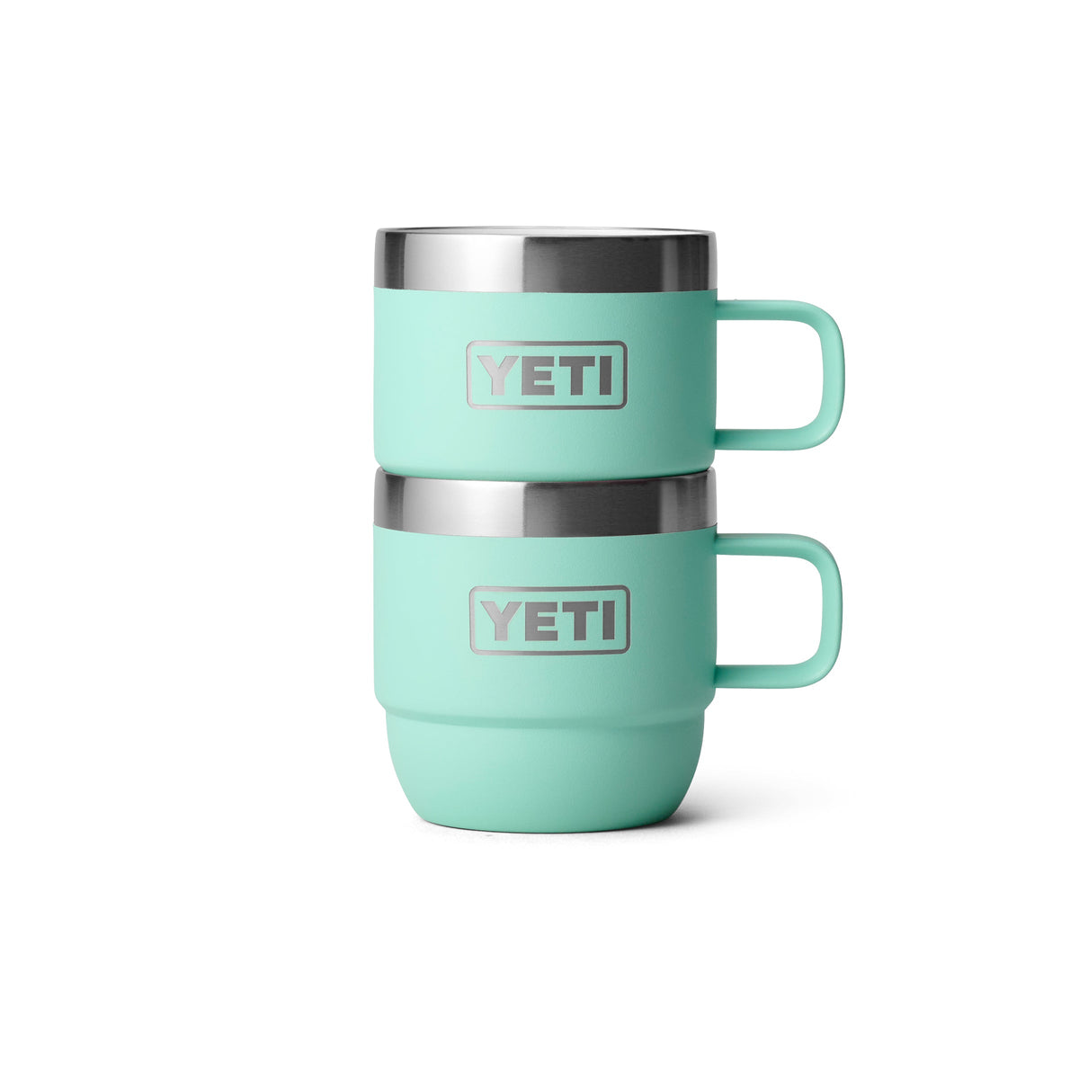 Zwei YETI® Espresso-Tassen Rambler 6 Oz (2er Pack) in Seafoam sind vor einem weißen Hintergrund gestapelt. Jeder Becher, mit silbernem Rand und Griff, verfügt über das YETI-Logo und doppelwandige Vakuumisolierung für Temperaturerhaltung.