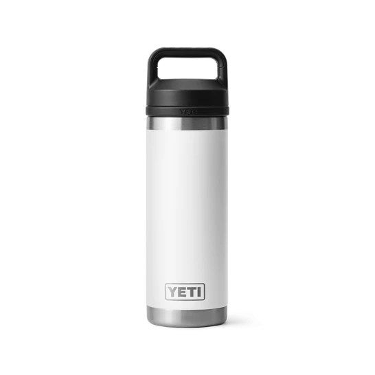 Eine YETI® Flasche Rambler 18 Oz - White mit doppelwandiger Vakuumisolierung und einem schwarzen Chug Cap Deckel steht aufrecht auf einem schlichten hellgrauen Hintergrund. Das YETI Logo erscheint in der Nähe des Bodens der Flasche.