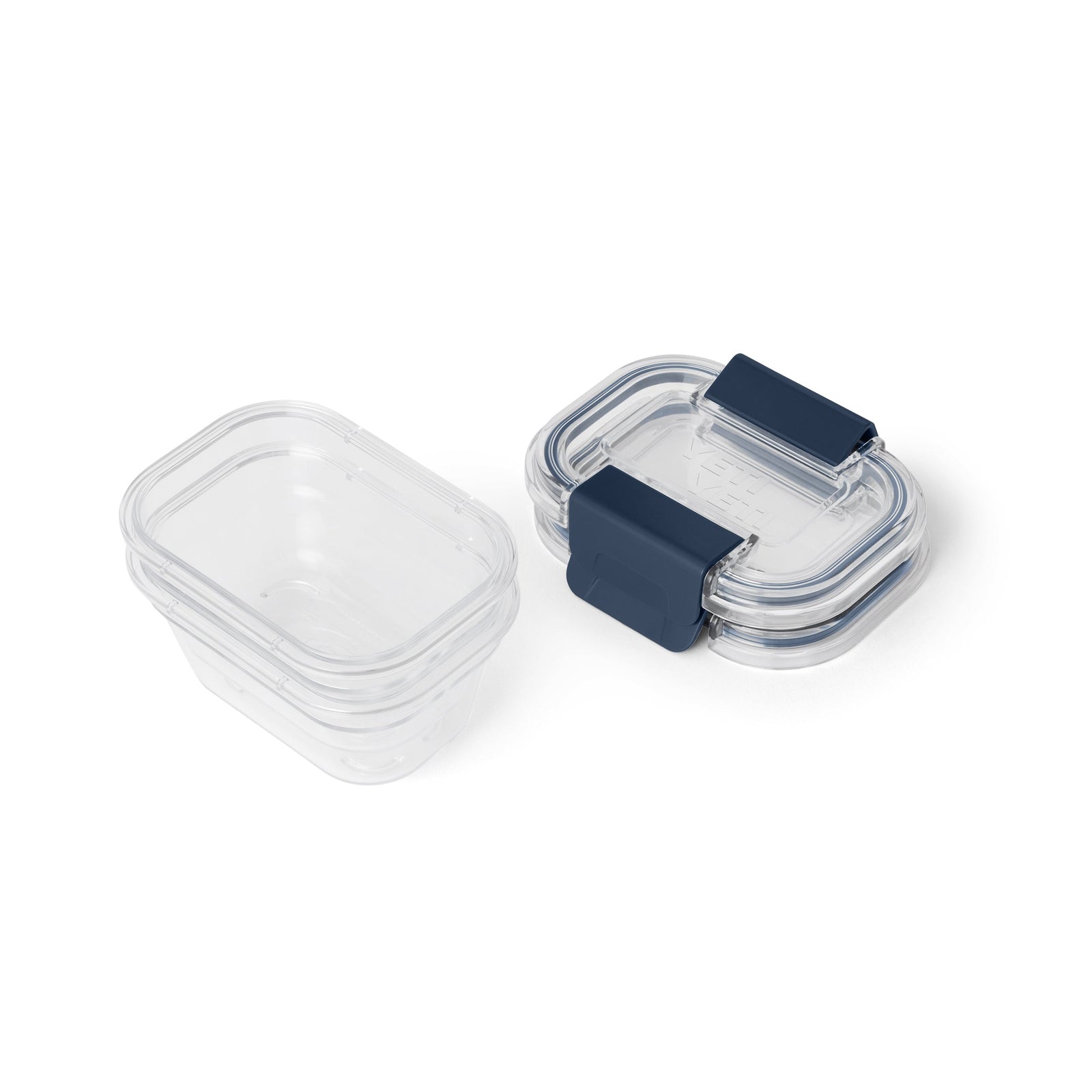 Zwei durchsichtige rechteckige YETI® Food Storage Small-Behälter, einer offen und einer mit blauem Schnappdeckel, stehen nebeneinander auf einem weißen Hintergrund. Diese BPA-freien, auslaufsicheren Behälter von YETI sind ideal, um Lebensmittel frisch zu halten.