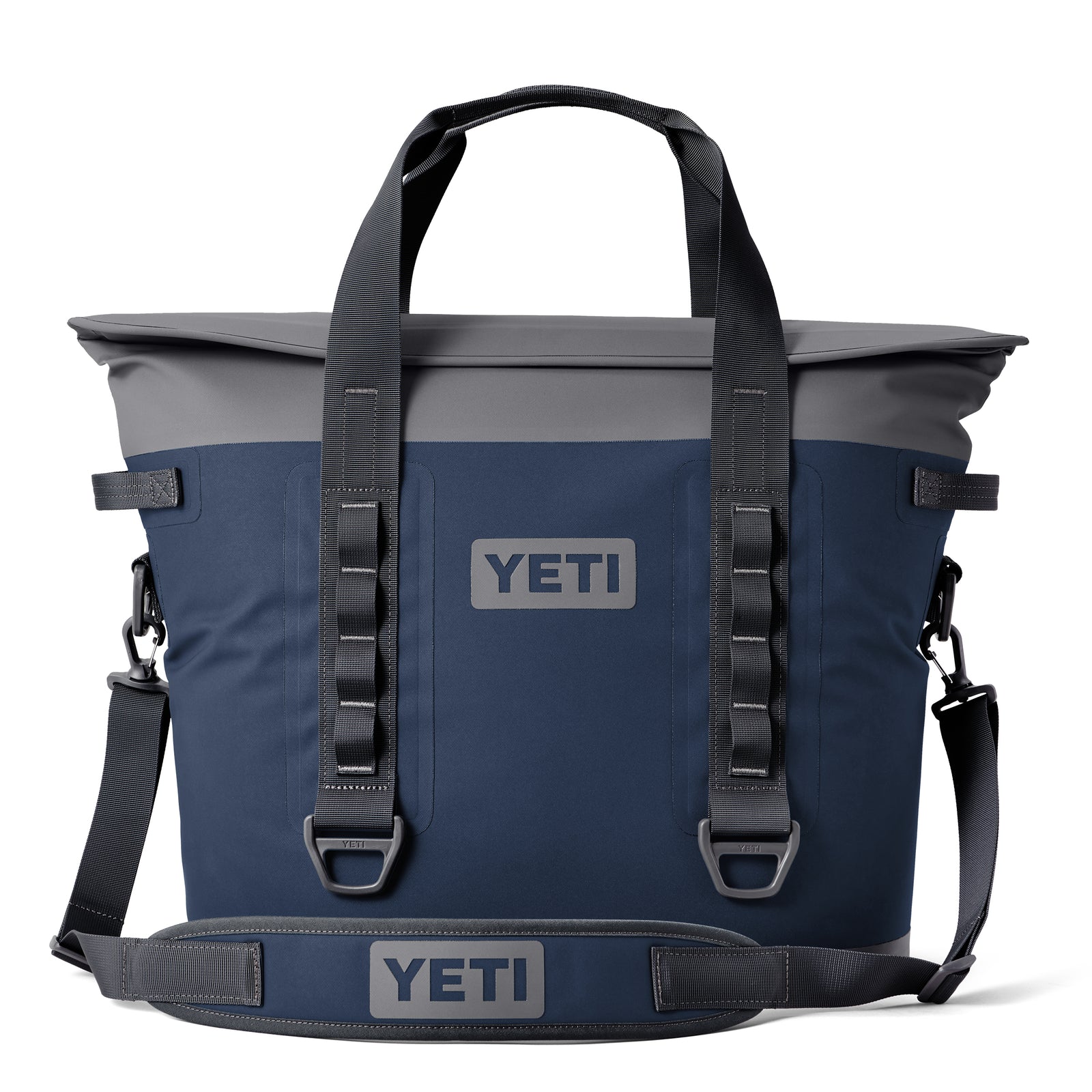 Die YETI® Hopper M30 Soft Cooler in Marineblau hat graue Akzente, schwarze Griffe, einen Schultergurt, MagShield Access und das YETI-Logo auf der Vorderseite und dem Gurt auf weißem Hintergrund.