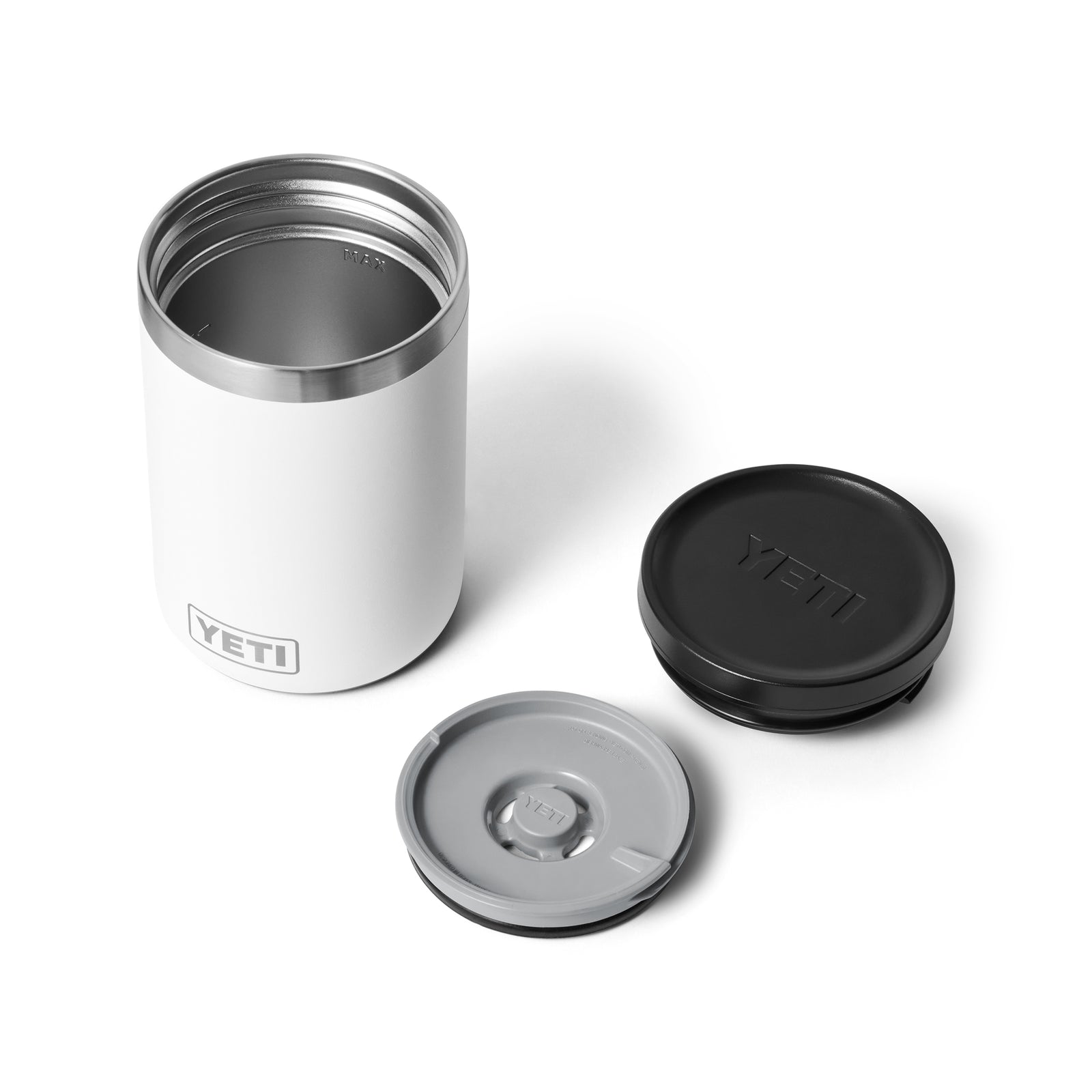 Ein weißer YETI® Isolierter Essensbehälter Rambler 16 oz steht mit abgenommenem Deckel auf einer weißen Fläche. Zwei Deckel - ein schwarzer und ein grauer, beide mit dem YETI-Logo - liegen daneben und sind die idealen Begleiter für Ihren Bedarf an isolierten Lebensmitteln.