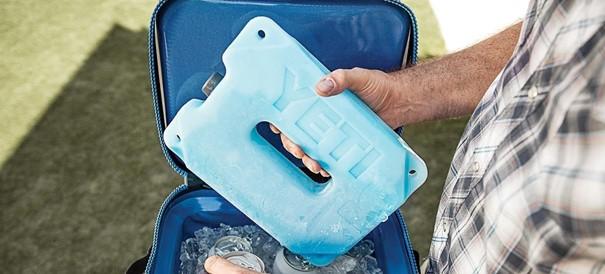Mit einem karierten Hemd genießt jemand einen sonnigen Tag im Freien, nachdem er den YETI® Kühlakku Ice Block 1 lb von YETI in seine Kühlbox gestellt hat, der Getränke und Eis perfekt kühlt.
