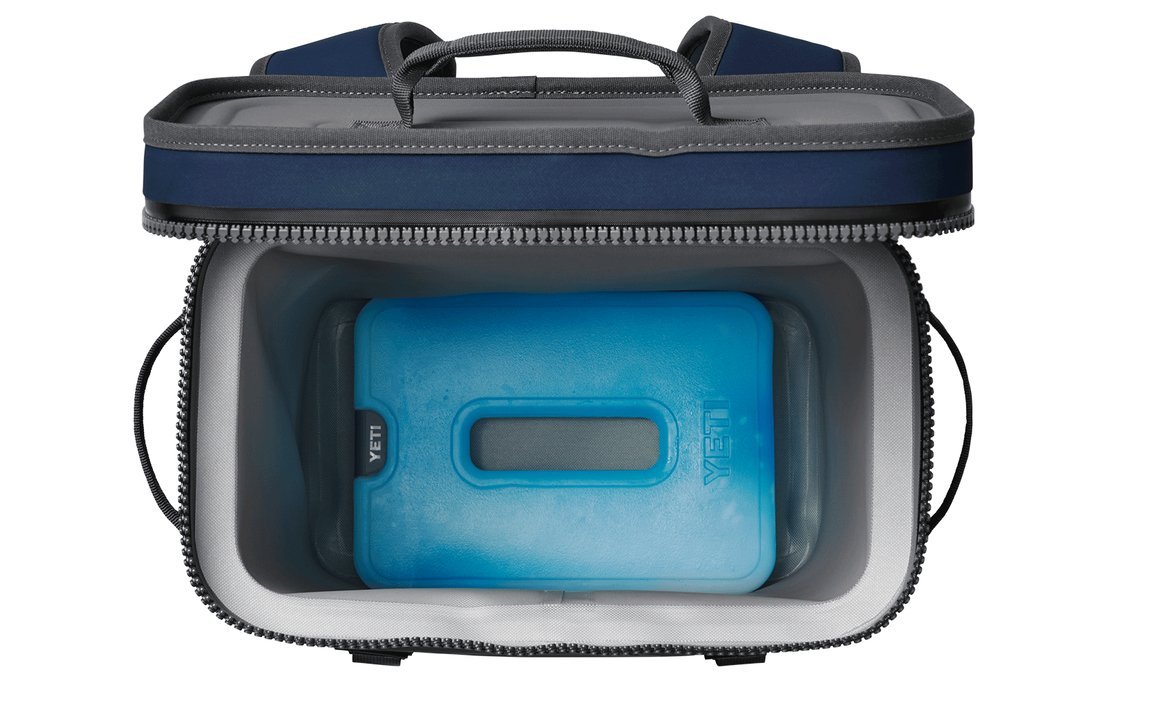 Eine offene Soft-Side-Kühltasche mit einer blauen YETI® Kühlakku Ice Sheet Large im Inneren, von oben betrachtet. Die navyfarbene Kühltasche hat graue Akzente, einen Griff und einen Reißverschluss am oberen Rand. Marke: YETI.