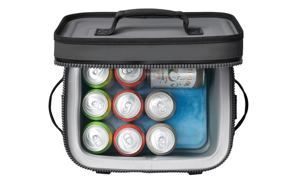 Draufsicht auf eine graue Soft-Side-Kühltasche mit schwarzen Griffen, gefüllt mit verschiedenen Getränkedosen und zwei blauen YETI® Kühlakku Ice Sheet Large Packs, mit geöffnetem Deckel.