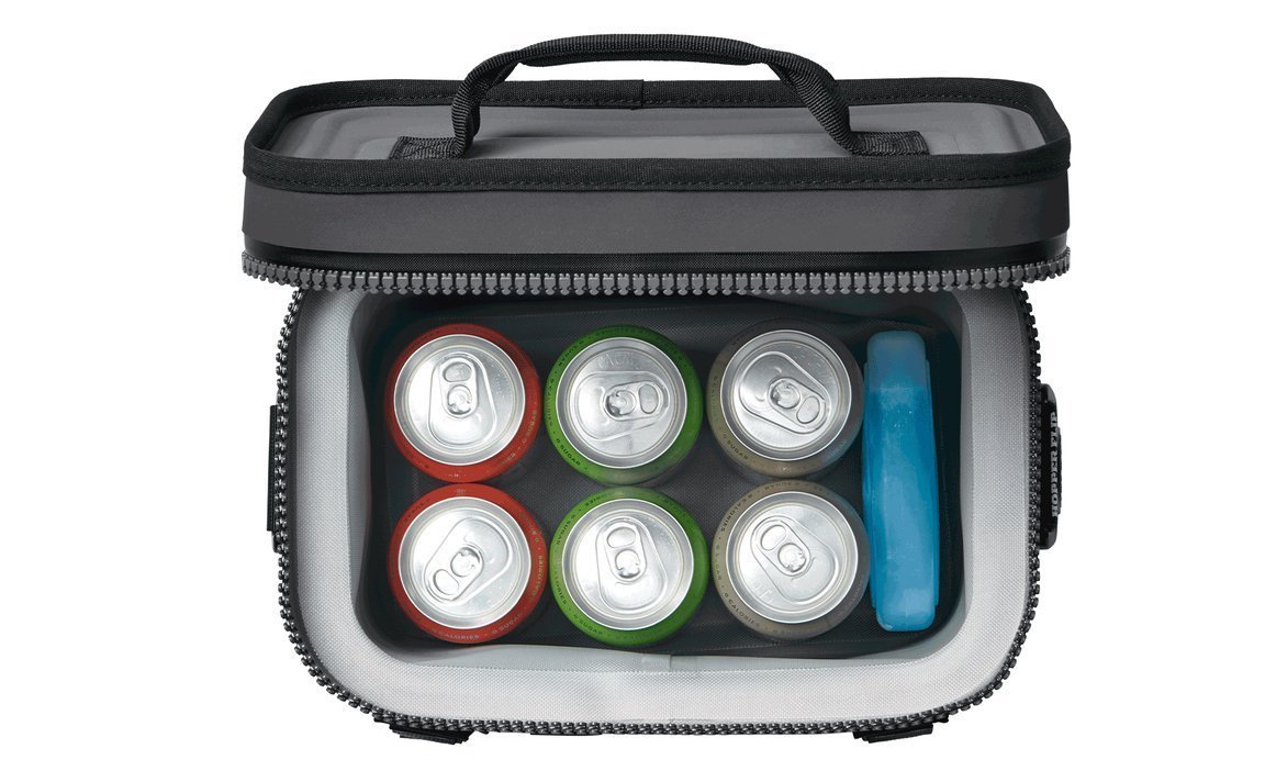Draufsicht auf eine offene Soft-Side-Kühltasche mit sechs verschiedenen Getränkedosen und einem blauen YETI® Kühlakku Ice Sheet Small Pack darin. Die Dosen haben silberne Deckel mit roten, grünen und goldenen Seiten. Marke: YETI.