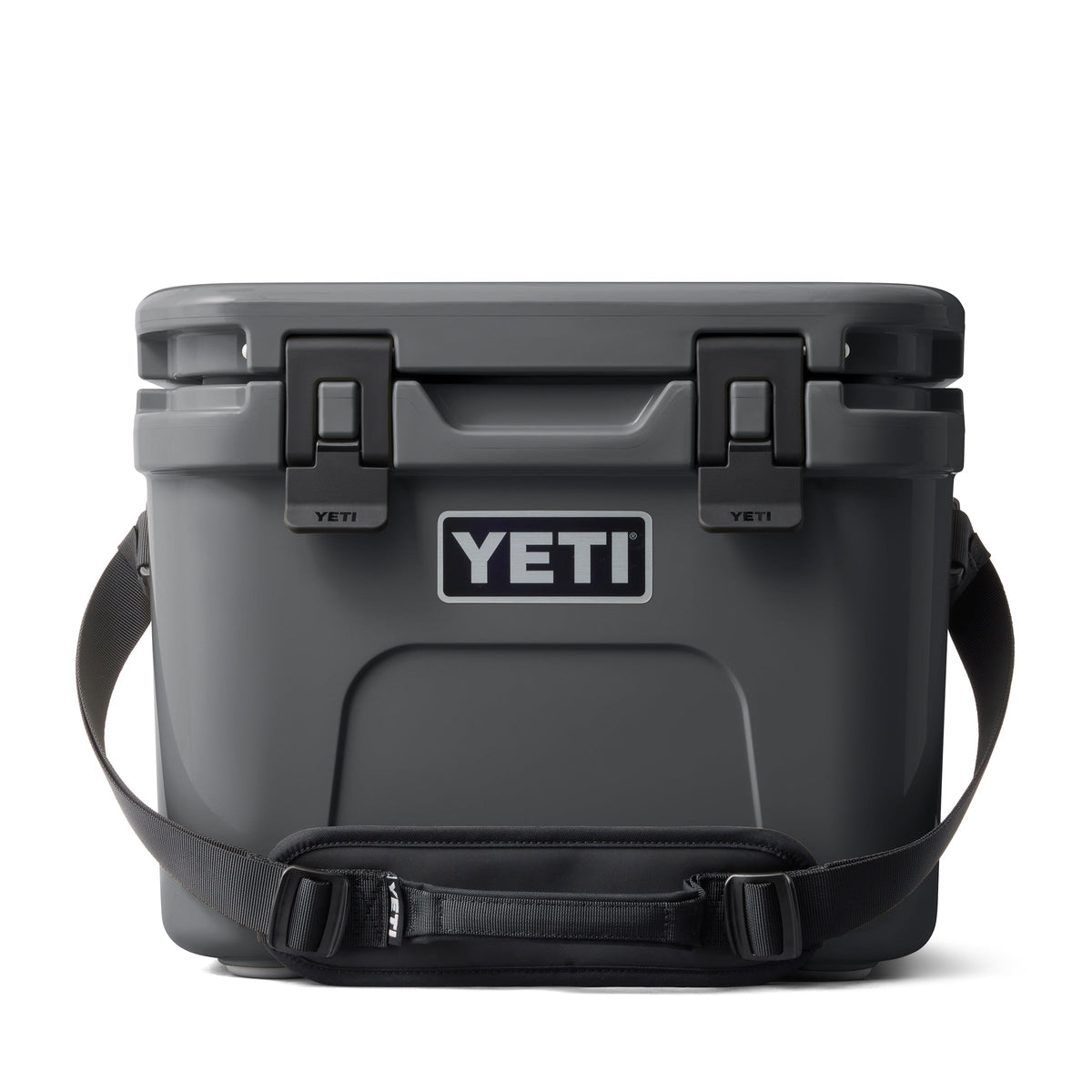 Die YETI® Kühlbox Roadie 15 in Anthrazit mit Trageriemen und Sicherheitsverschlüssen ist auf weißem Hintergrund zu sehen. Das kultige YETI-Logo prangt auf der Vorderseite.