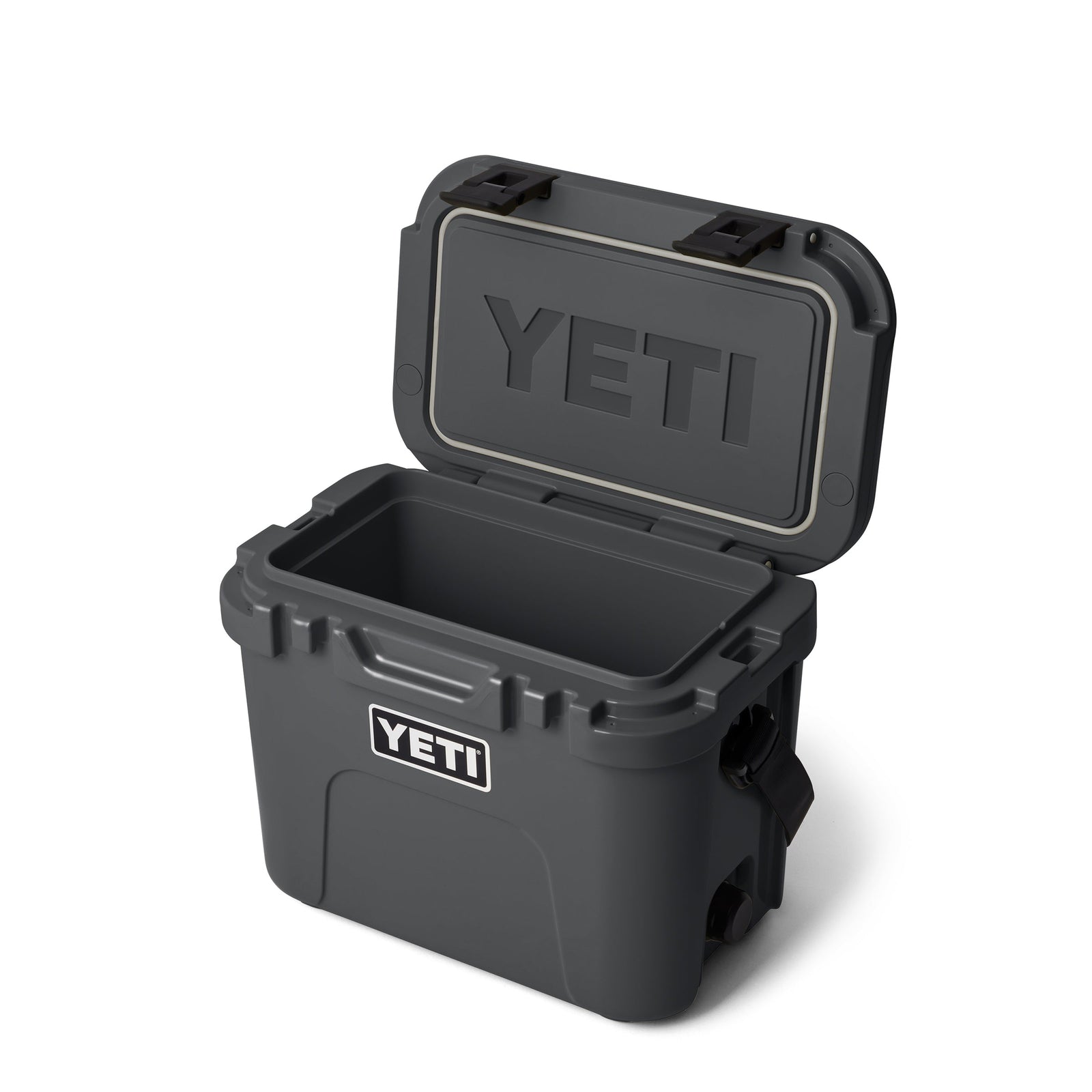 Eine YETI® Kühlbox Roadie 15 in Charcoal mit geöffnetem Deckel offenbart einen geräumigen Innenraum. Das YETI-Logo befindet sich auf der Vorderseite der tragbaren Kühlbox und auf der Innenseite des Deckels.