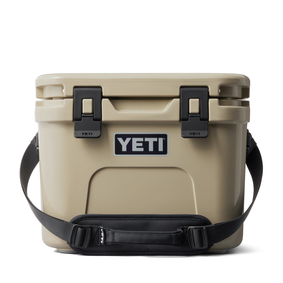 Eine hellbraune YETI® Kühlbox Roadie 15 mit schwarzen Verschlüssen, einem schwarzen Schultergurt und einem auffälligen YETI-Logo auf der Vorderseite ist vor einem weißen Hintergrund zu sehen.