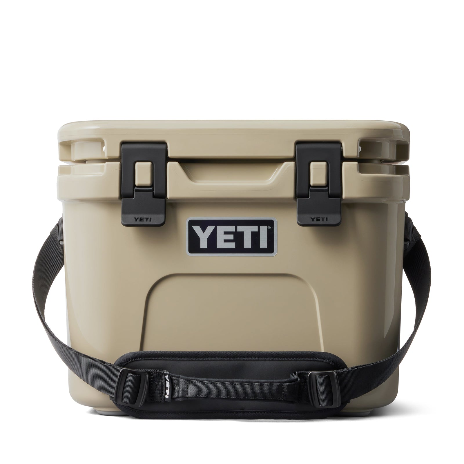 Eine hellbraune YETI® Kühlbox Roadie 15 mit schwarzen Verschlüssen, einem schwarzen Schultergurt und einem auffälligen YETI-Logo auf der Vorderseite ist vor einem weißen Hintergrund zu sehen.