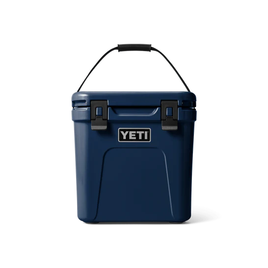 Eine YETI® Kühlbox Roadie 24 in Navy mit schwarzem Griff und zwei schwarzen Verschlüssen, ausgestattet mit PermaFrost Isolierung, ist auf einem schlichten weißen Hintergrund abgebildet.